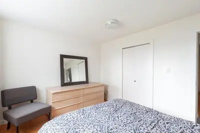 a bedroom with a bed and a chair and a mirror at PNE Delight in Vancouver