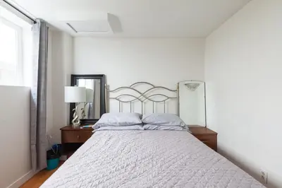 a white bedroom with a large bed with white sheets at PNE Delight in Vancouver