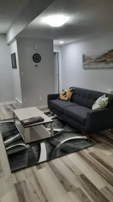 a living room with a black couch and a table at Carsonway Basement Suite in Edmonton