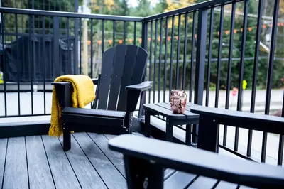 a deck with a chair and a table with a candle at Cedar and Loam by Revelstoke Vacations in Revelstoke
