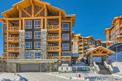 a large building in the snow with a ski lift at Stonegate Resort Unit B408 in Big White