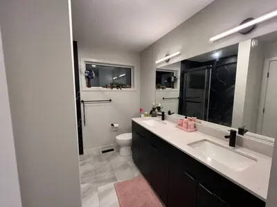 a bathroom with two sinks and a toilet and a mirror at ZierHomes in Devon
