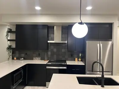 a kitchen with black cabinets and a stainless steel refrigerator at ZierHomes in Devon