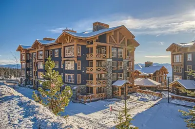 a large building with snow in front of it at Stonegate Resort Unit B105 in Big White