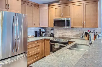 a kitchen with wooden cabinets and a stainless steel refrigerator at Stonegate Resort Unit B303 in Big White