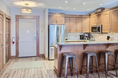 a kitchen with wooden cabinets and bar stools at Stonegate Resort Unit B103 in Big White