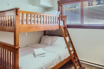 a bunk bed with a ladder next to a window at Stonegate Resort Unit C202 in Big White