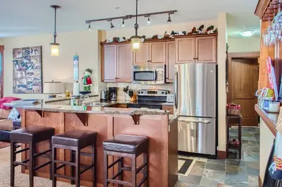 a kitchen with wooden cabinets and a stainless steel refrigerator at Stonegate Resort Unit C103 in Big White