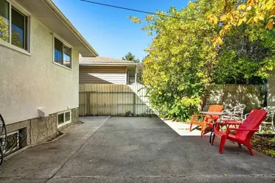 a patio with two red chairs and a table at Voyager's Hub- Calgary InnerCity 3BD 4Bed Sleeps 8 in Calgary
