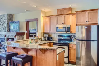 a kitchen with wooden cabinets and a stainless steel refrigerator at Stonegate Resort Unit A202 in Big White