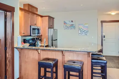 a kitchen with a counter with bar stools at Stonegate Resort Unit A202 in Big White