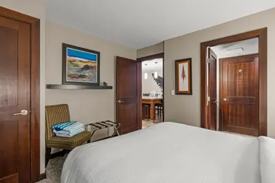 a bedroom with a bed and a chair and a door at Stylish Family Condo at Beachfront Resort in Parksville