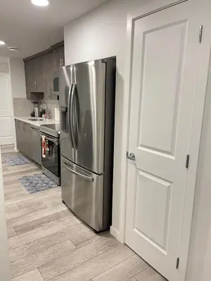 a kitchen with a stainless steel refrigerator next to a door at Exquisite Basement Suite, 7mins away to Landmark Cinema and Malls in Calgary