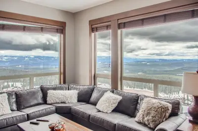 a living room with a couch and large windows at Stonegate Resort Unit B401 in Big White