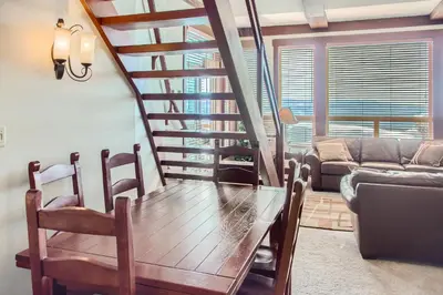 a living room with a wooden table and a staircase at Stonegate Resort Unit A402 in Big White