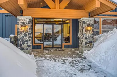 a snow covered entrance to a building with a glass door at Stonegate Resort Unit C304 in Big White