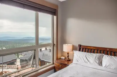 a bedroom with a bed and a large window at Stonegate Resort Unit B108 in Big White
