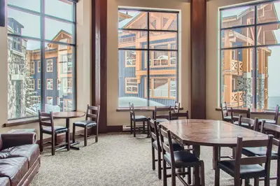 a restaurant with tables and chairs and large windows at Stonegate Resort Unit B108 in Big White