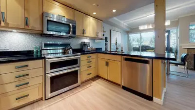a kitchen with wooden cabinets and stainless steel appliances at LAGOONS 20 Village location Rare 5BDR Condo With Private Hot Tub in Whistler