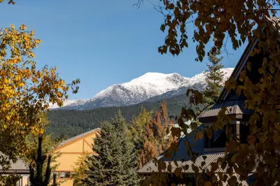 a snow covered mountain in the distance behind a building at LAGOONS 20 Village location Rare 5BDR Condo With Private Hot Tub in Whistler