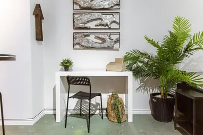 a white desk with a chair and a plant at Chic & Cozy Loft near Rogers Place, LRT, Jasper Ave in Edmonton