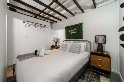 a bedroom with a white bed and a green painting on the wall at Chic & Cozy Loft near Rogers Place, LRT, Jasper Ave in Edmonton