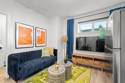 a living room with a blue couch and a large tv at Jungle House, AirCon, Sleeps 8, Near WEM & DT! in Edmonton
