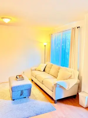 a living room with a white couch and a blue ottoman at Private Room In The Heart Of The City in Vancouver