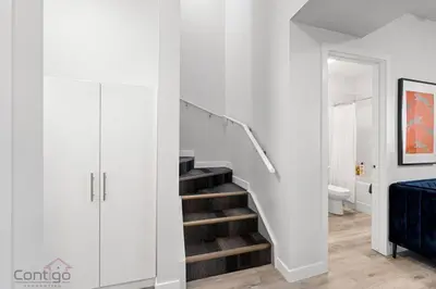 a white hallway with a staircase in a house at The Den, Centrally Located Suite, King Bed, WiFi! in Edmonton