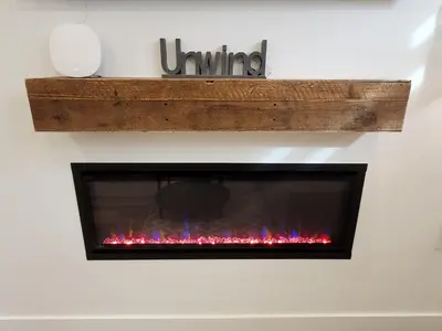 a fireplace on a white wall with red flames at 2BR Detached Guesthouse - Free Parking -10 mins to YVR & Downtown in Vancouver