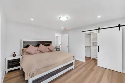 a white bedroom with a large bed with pink pillows at Your stay at Haysboro in Calgary