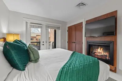 a bedroom with a bed with a fireplace and a television at Luxury Rockies Retreat 1BR with Views in Canmore
