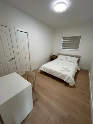 a white bedroom with a bed and a table at Waverley Guest Room in Vancouver in Vancouver