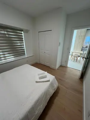 a white bedroom with a bed with two towels on it at Waverley Guest Room in Vancouver in Vancouver