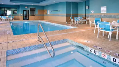 a pool with chairs and tables in a hotel room at Holiday Inn Hotel & Suites Edmonton Airport Conference Centre by IHG in Nisku