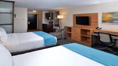 a hotel room with a bed and a desk with a television at Holiday Inn Hotel & Suites Edmonton Airport Conference Centre by IHG in Nisku