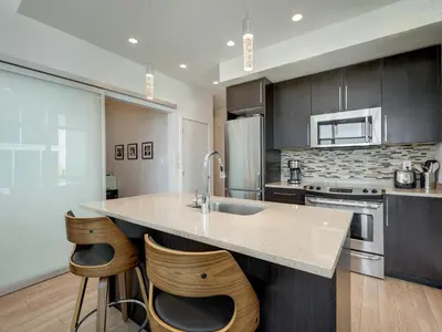 a kitchen with a sink and two stools at The Bohemian, min 30-Day Stay with Breathtaking Views and Home Office by Victoria Prime! in Victoria