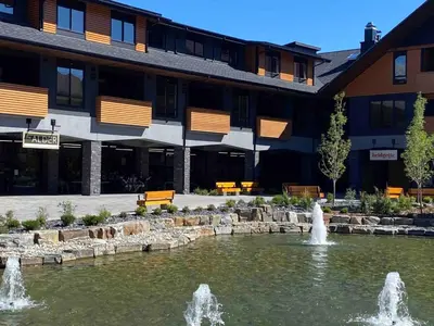 a fountain in a pond in front of a building at Le Bucheron Stunning Spring Creek Luxury condo in Canmore