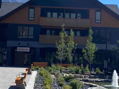 a building with benches and a fountain in front of it at Le Bucheron Stunning Spring Creek Luxury condo in Canmore