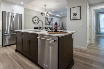 a kitchen with a sink and a refrigerator at Le Bucheron Stunning Spring Creek Luxury condo in Canmore