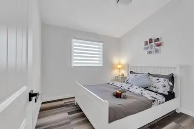 a white bedroom with a bed with a window at ModernOasis with AC&MovieRoom close to Downtown15' Banff 60' in Calgary