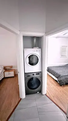 a room with a washing machine in a room with a bed at The warm and lovely coach home in Vancouver