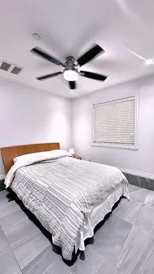 a bedroom with a bed with a ceiling fan at The warm and lovely coach home in Vancouver