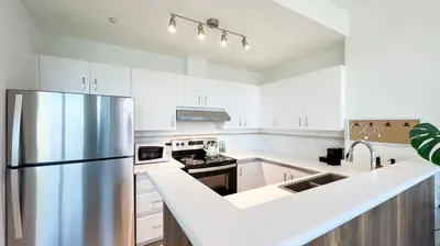 a kitchen with white cabinets and a stainless steel refrigerator at Stunning 1-Bedroom Condo in the Heart of Vancouver in Vancouver
