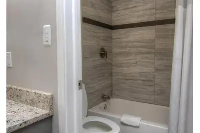 a bathroom with a tub and a toilet and a sink at Victorian Motel & RV Park by Capital O in Grand Forks
