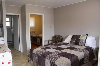 a bedroom with a bed and a chair in it at Victorian Motel & RV Park by Capital O in Grand Forks