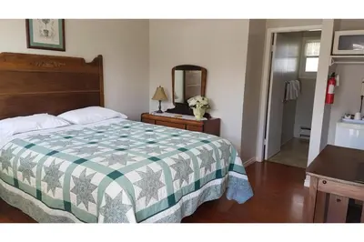 a bedroom with a bed with a green and white quilt at Victorian Motel & RV Park by Capital O in Grand Forks