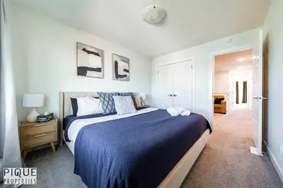 a bedroom with a large bed with a blue blanket at Modern Retreat - 3 King Beds - Garage - WiFi - Sleeps 10 in Edmonton