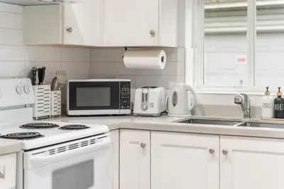 a white kitchen with white cabinets and a microwave at Cozy and Modern 2br guesthouse in Vancouver