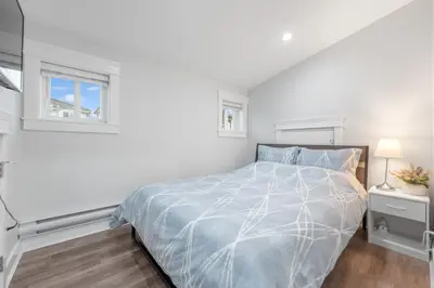 a white bedroom with a bed and a window at Cozy and Modern 2br guesthouse in Vancouver